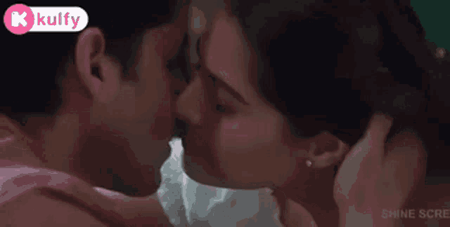 a man and a woman are kissing on a bed in a movie .