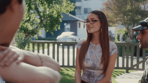 a woman wearing glasses is talking to a man wearing a hat