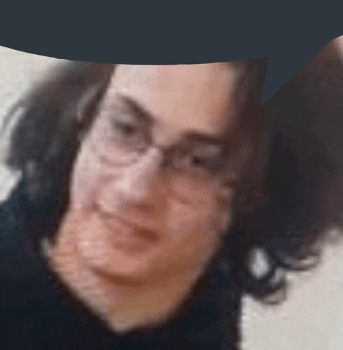 a blurry photo of a man wearing glasses and a black shirt