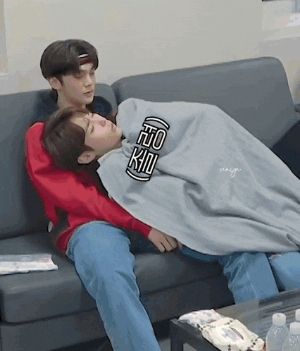 two young men are laying on a couch with one wearing a shirt that says " to kill " on it