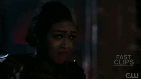 a woman is crying in a dark room with a sword in her hand .