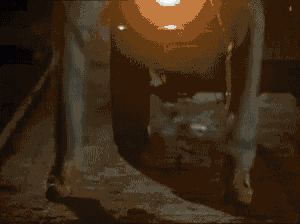 a man in a white shirt is sitting in a dark room with a shadow on his face .