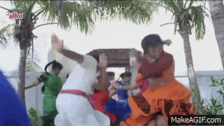a group of people are dancing in front of palm trees in a park .