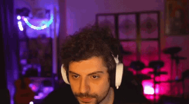 a man with a beard wearing headphones is pointing at the camera .