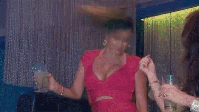 a woman in a red dress is holding a drink and dancing in a club .