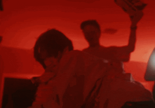a man and a woman are standing in a dark room with a red light behind them