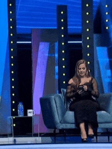 a woman sits on a couch in front of a sign that says abc on it