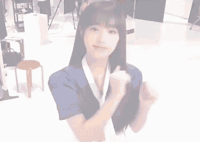a woman in a blue shirt and white tie is giving a thumbs up sign