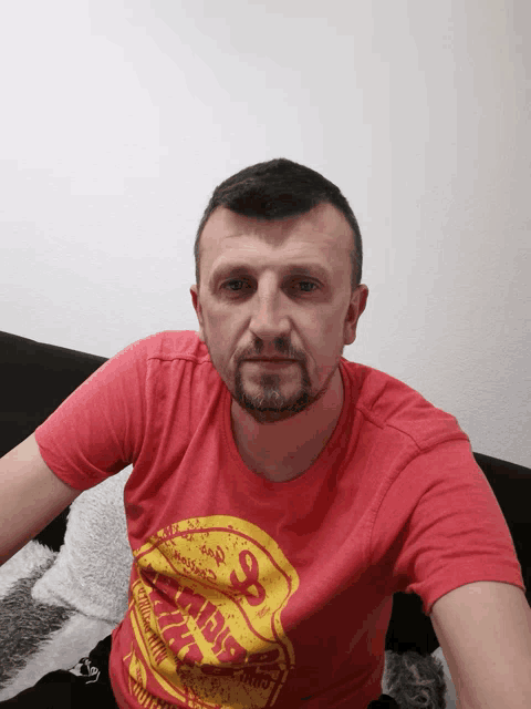 a man wearing a red t-shirt with a yellow s on it
