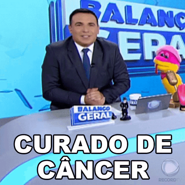 a man in a suit and tie sits at a desk with a sign that says balance geral