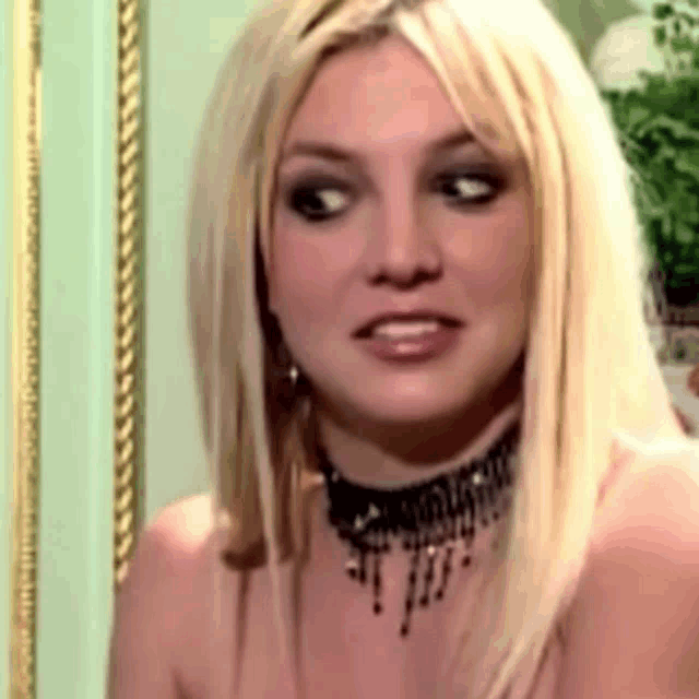 britney spears is wearing a choker and earrings and looking at the camera .