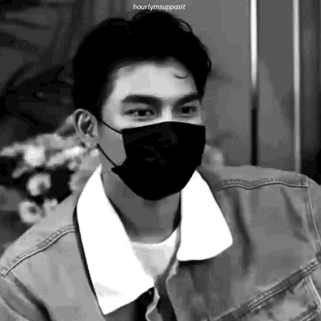 a black and white photo of a young man wearing a mask .