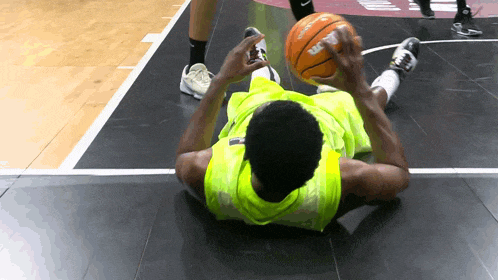 a basketball player is laying on the floor holding a spalding ball
