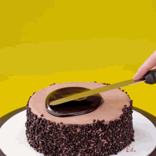 a person is cutting a cake with a knife and the word ea is on the bottom