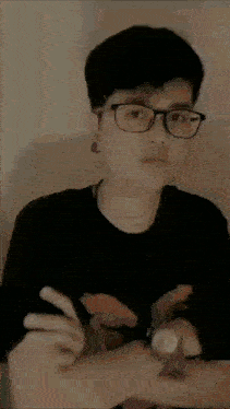 a young man wearing glasses and a black shirt is looking at the camera .