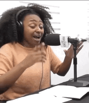 a woman wearing headphones is singing into a microphone in a studio .