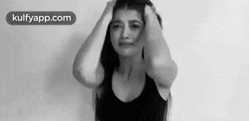 a black and white photo of a woman holding her head in her hands .