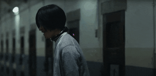 a man is standing in the middle of a long hallway in a prison .