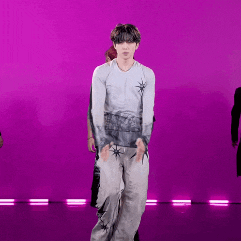 a man in a white shirt and grey pants is dancing on a purple background .