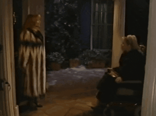 a woman in a fur coat is standing in front of a man in a wheelchair