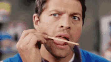 a man is sticking his tongue out while holding a toothpick in his mouth .