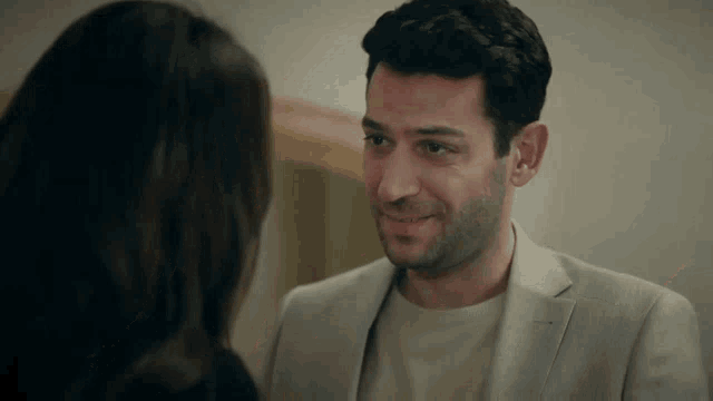a man in a suit smiles at a woman in a black shirt