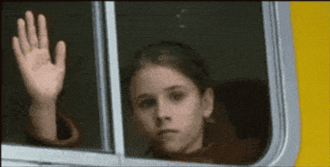 a young girl waving her hand out of a bus window