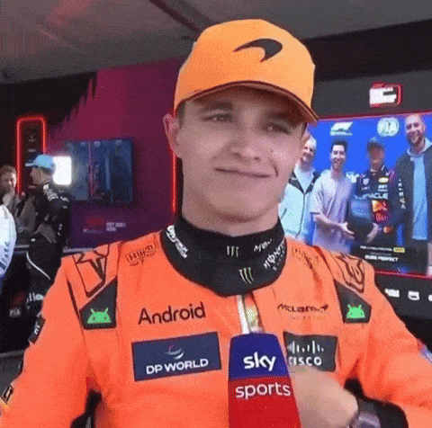 a man wearing an orange hat is holding a microphone in front of a screen .