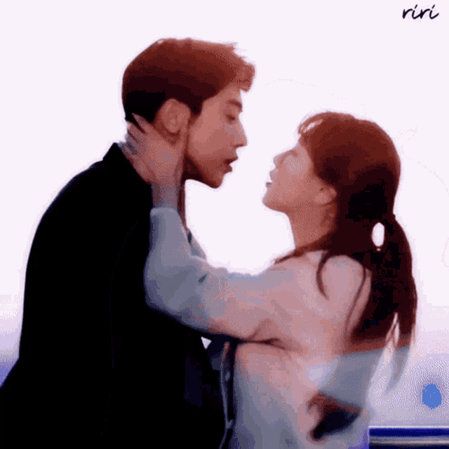 a man and a woman are kissing each other on the forehead .