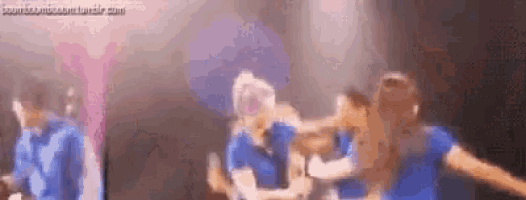 a group of people are dancing on a stage in a dark room .