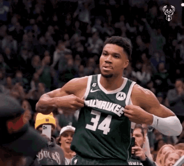 a man in a green milwaukee jersey takes off his shirt