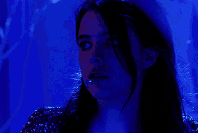 a woman is looking down in a blue light