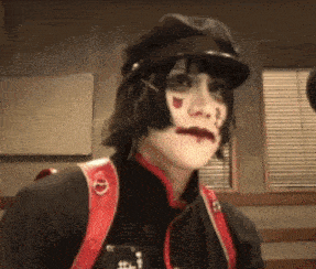 a woman wearing a black hat and a red backpack is looking at the camera