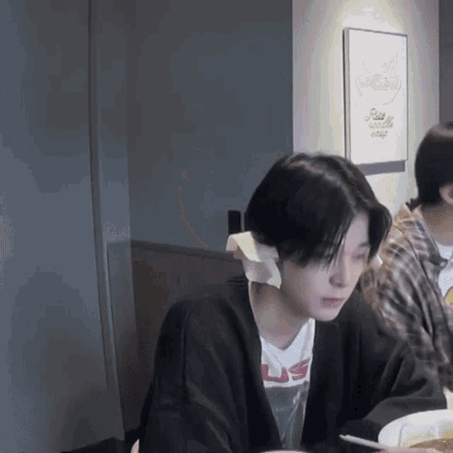 a woman with a bandage on her ear is sitting at a table in front of a sign that says ready to eat soup