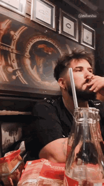 a man sitting at a table with a bottle of coca cola