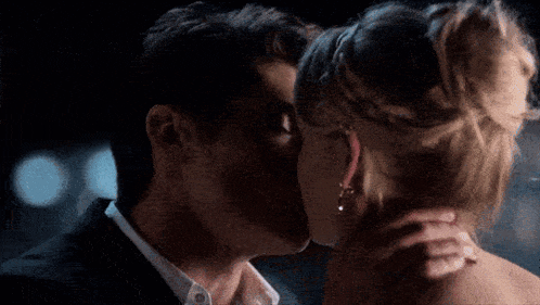 a man and a woman are kissing each other in a dark room .