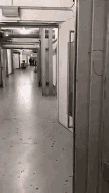 a person is walking down a hallway in a building with a door open .