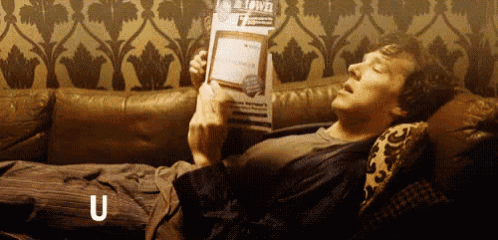 a man is laying on a couch reading a magazine and the letter u is above his head