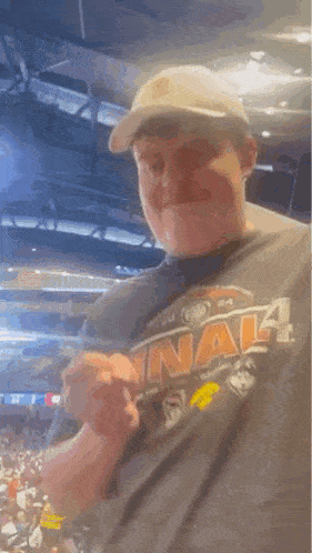 a man wearing a hat and a t-shirt is standing in front of a crowd at a sports game .