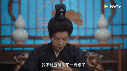 a man in a traditional costume is sitting in front of a screen that says wetv
