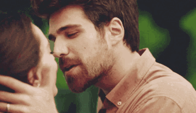a man with a beard kissing a woman on the cheek