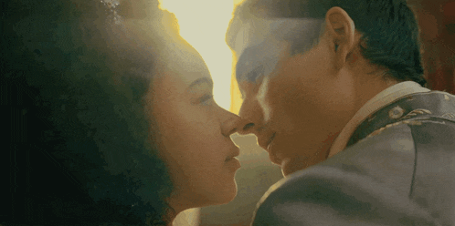 a man and woman kissing with the sun shining through the window