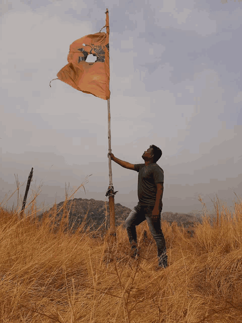 a man stands in a field holding an orange flag with a hole in it that says ' freedom ' on it