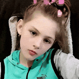 a young girl wearing a blue puma sweatshirt takes a selfie
