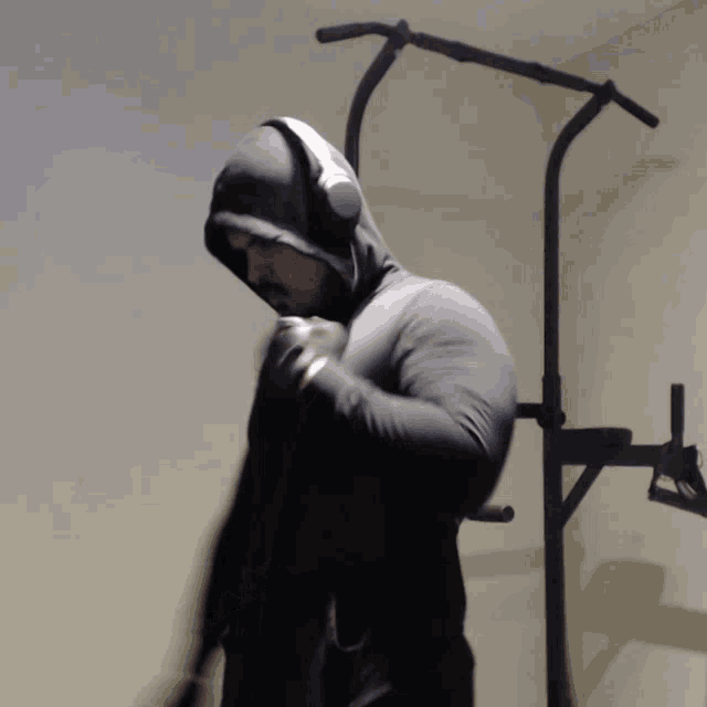 a man wearing a hoodie and boxing gloves holds a dumbbell