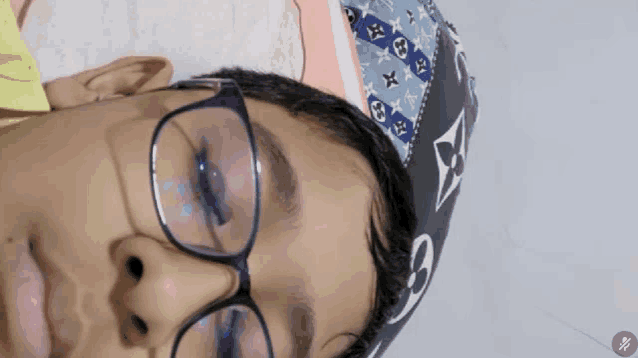 a boy wearing glasses and a louis vuitton hat looks down