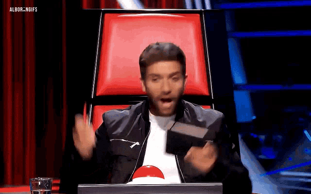 a man is sitting in a chair with his mouth open and the words albor.noifs on the bottom right