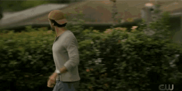 a man wearing a baseball cap is running in front of a cw sign