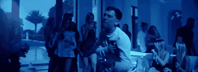 a group of people are gathered in a room with a blue light shining on them