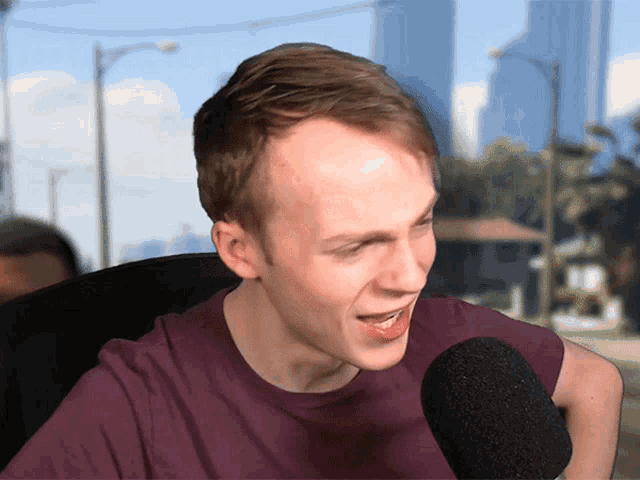 a man in a purple shirt talking into a microphone